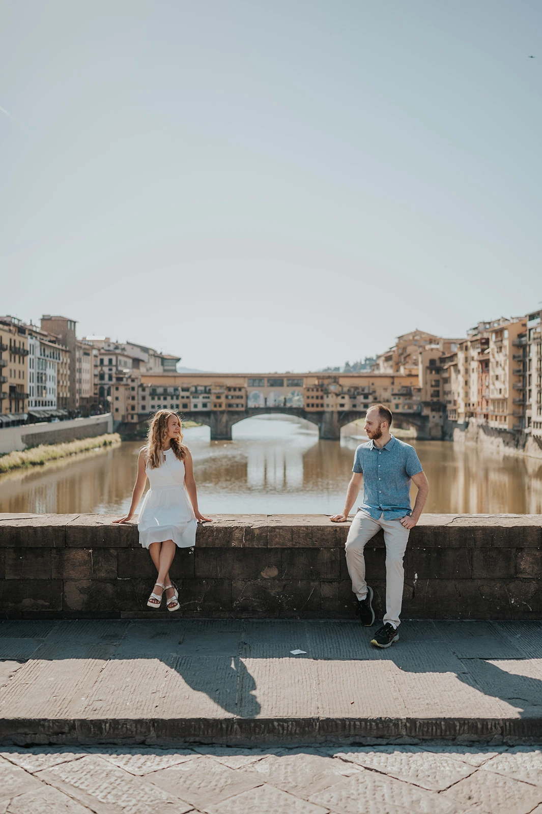 Una coppia seduta lungo l’Arno con il Ponte Vecchio di Firenze sullo sfondo