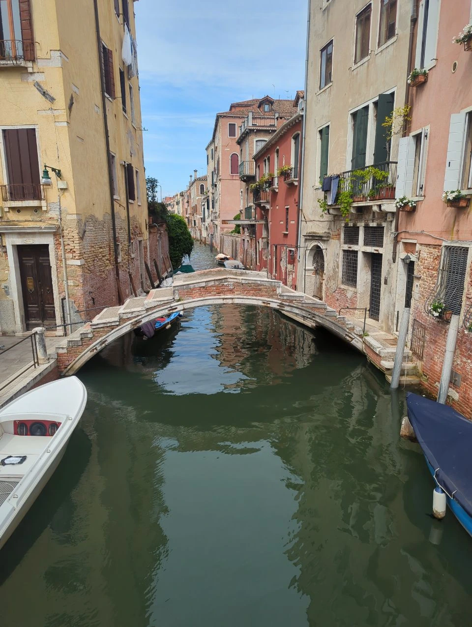 Stone footbridge over a quiet canal between colourful buildings in Venice