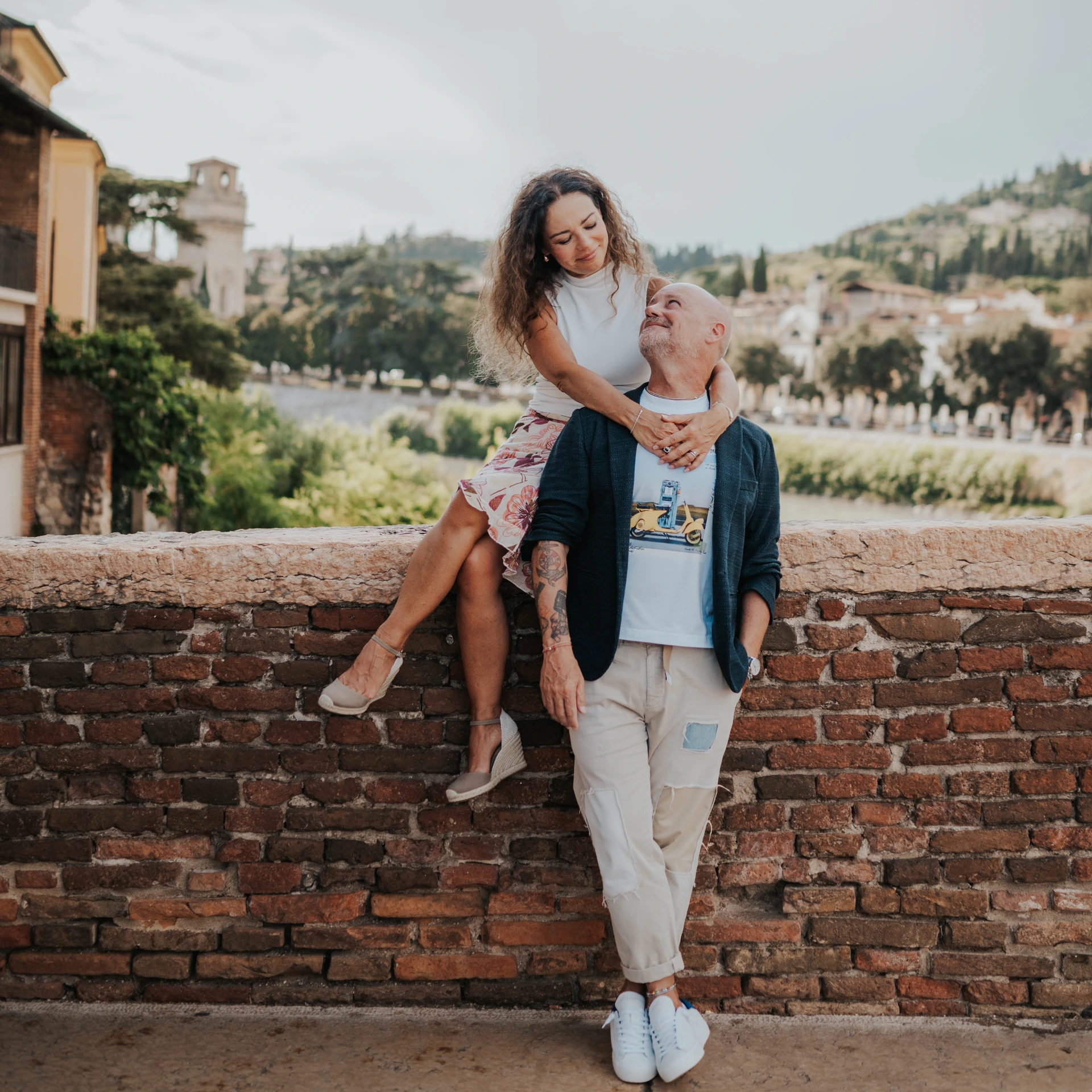 Couple beside a brick wall overlooking the Adige in Verona