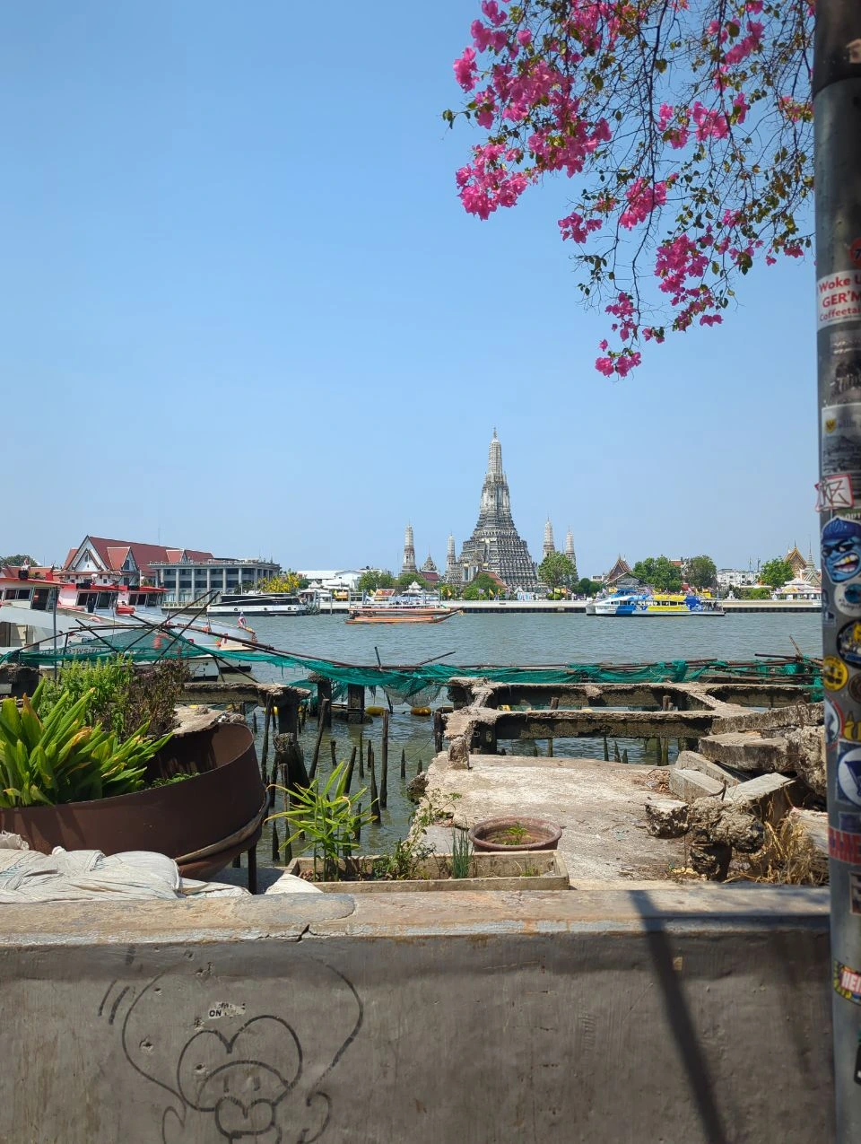 Wat Pho vs Wat Arun Photos - Cross-River View Wat Arun rises across Bangkok’s Chao Phraya River, with boats crossing the water between the two temple areas.