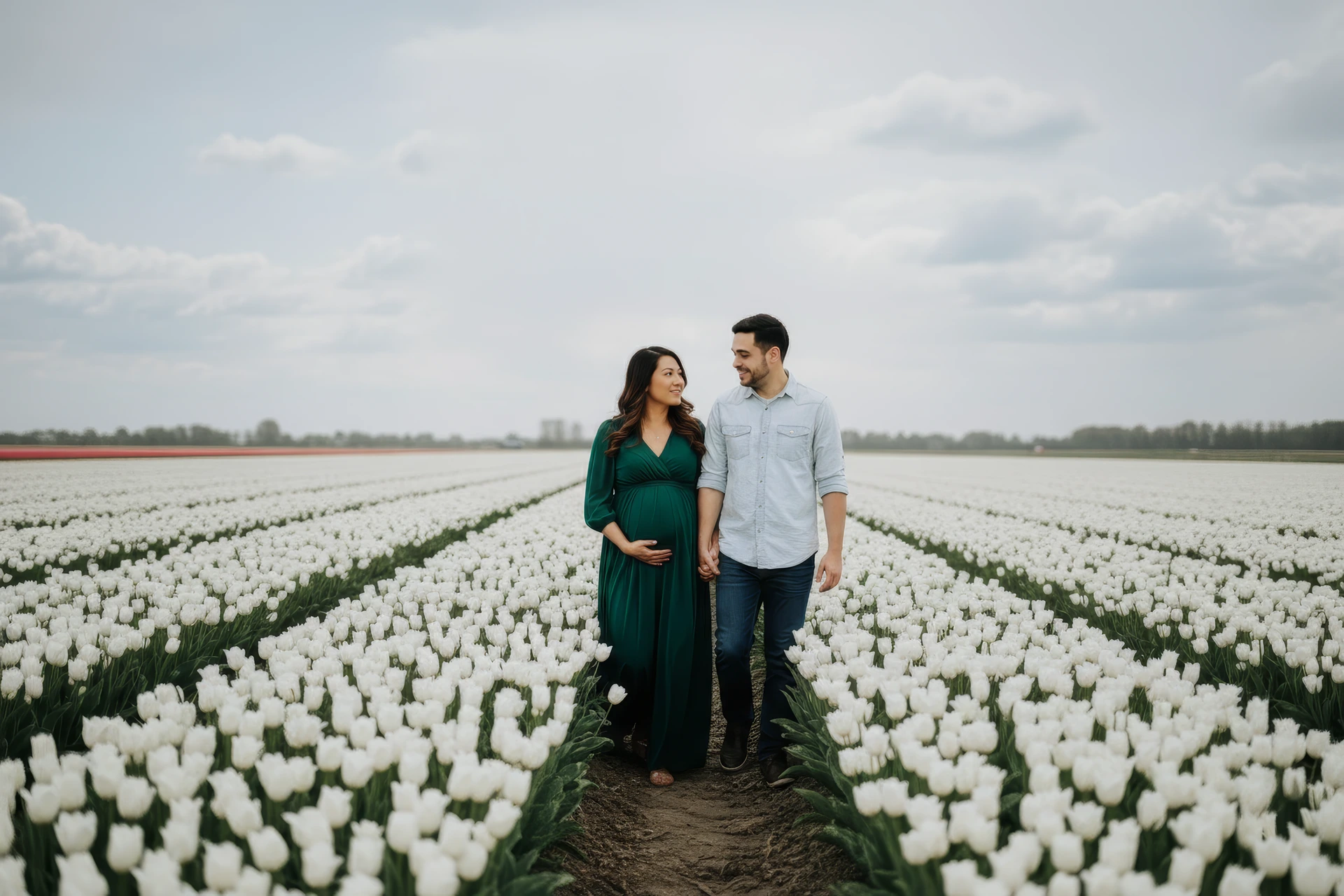 Koppel dat naar elkaar lacht tijdens een zwangerschapsshoot in Amsterdam bij Damrak